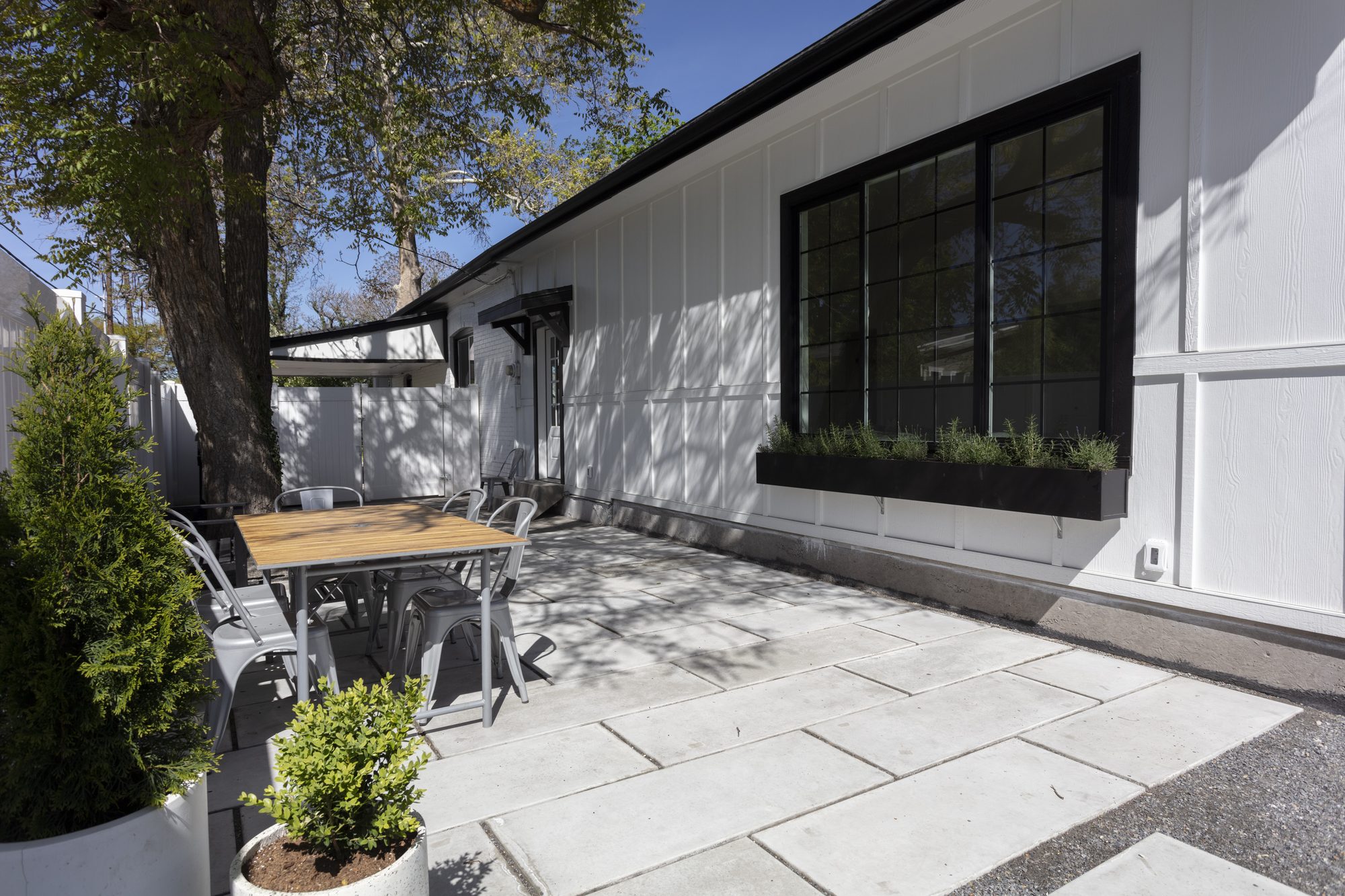 Covered patio and exterior renovation with black-framed windows and stone paving
