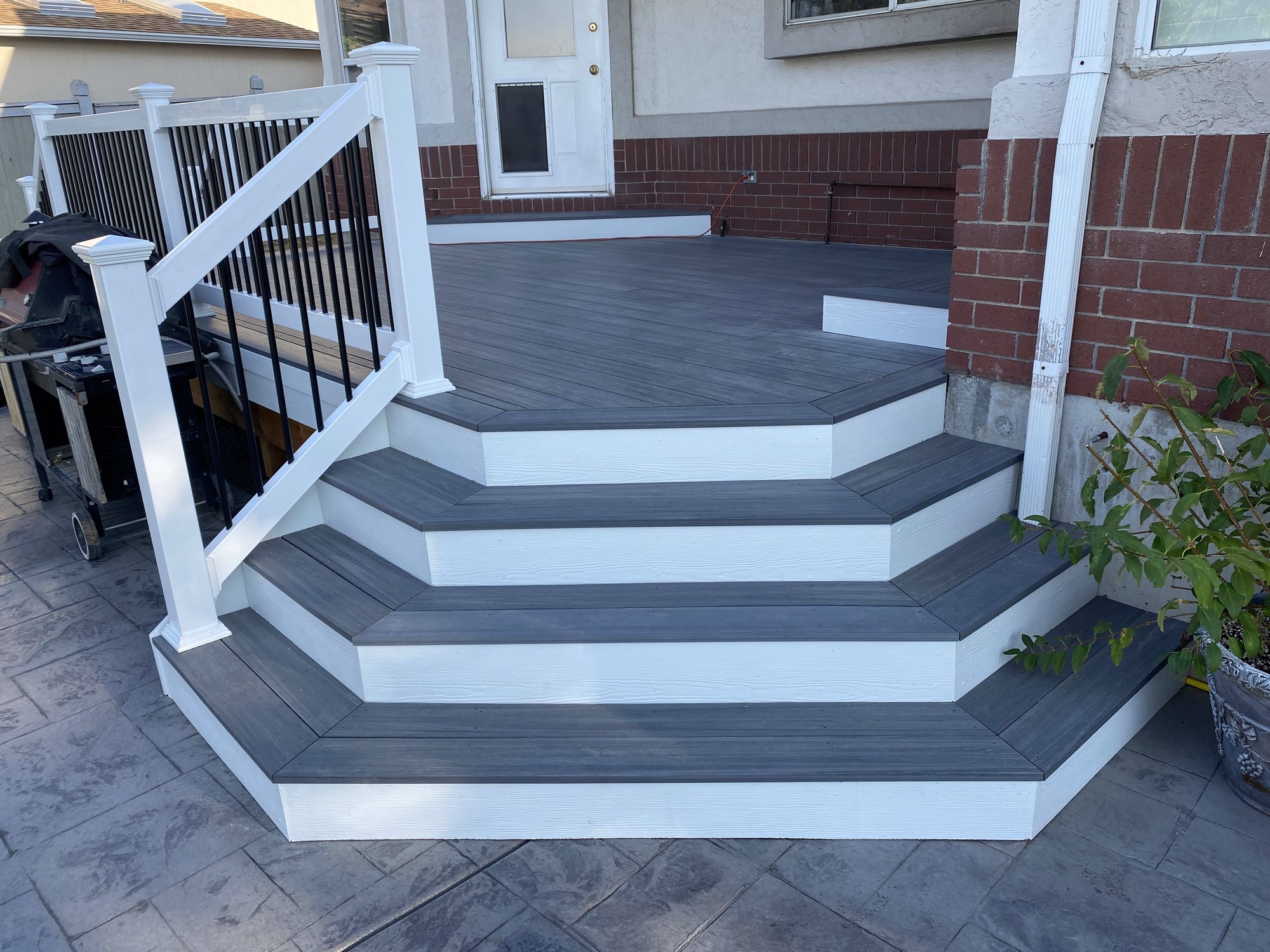 Composite deck with cascading angled steps, grey decking, white risers and black metal railing