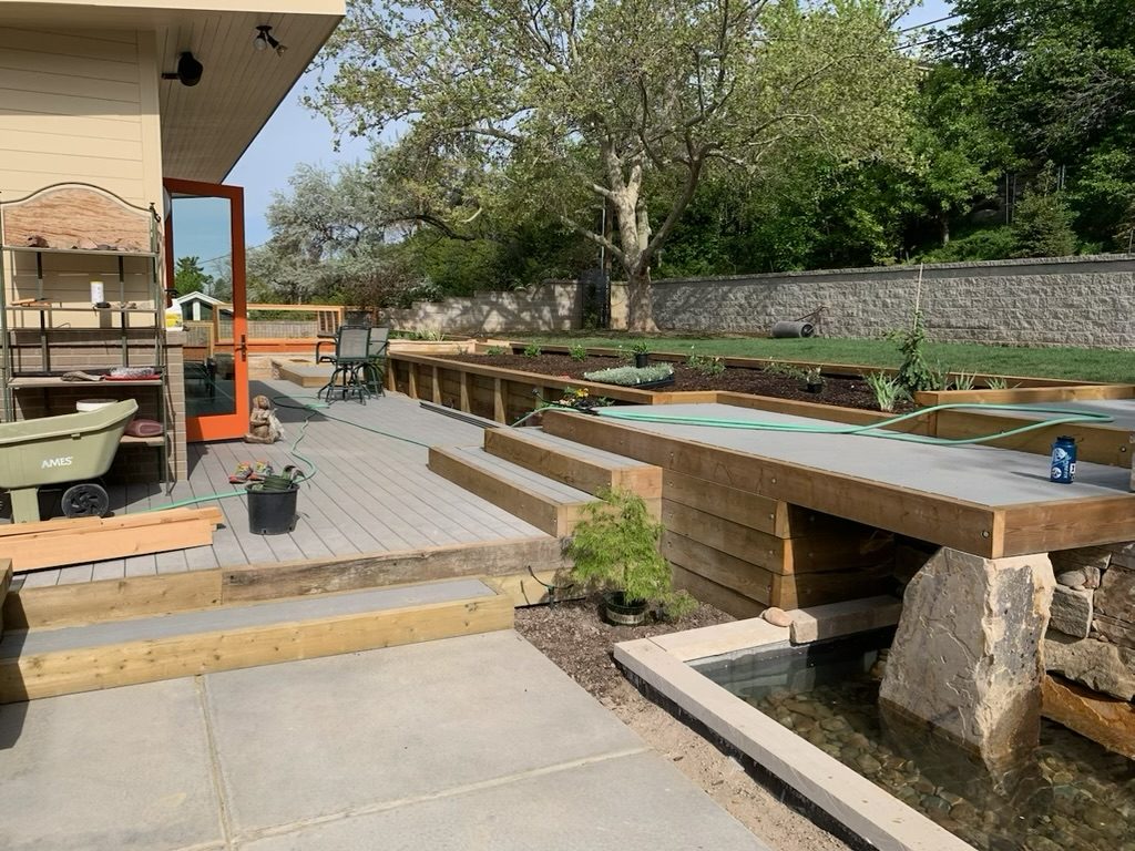 Backyard after a whole-home remodel, with a composite deck, raised planters and a water feature
