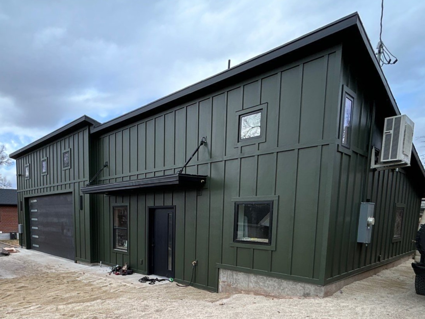Detached shop and ADU in dark green board-and-batten siding with a black overhead door, built in the Foothill area of Salt Lake City, Utah