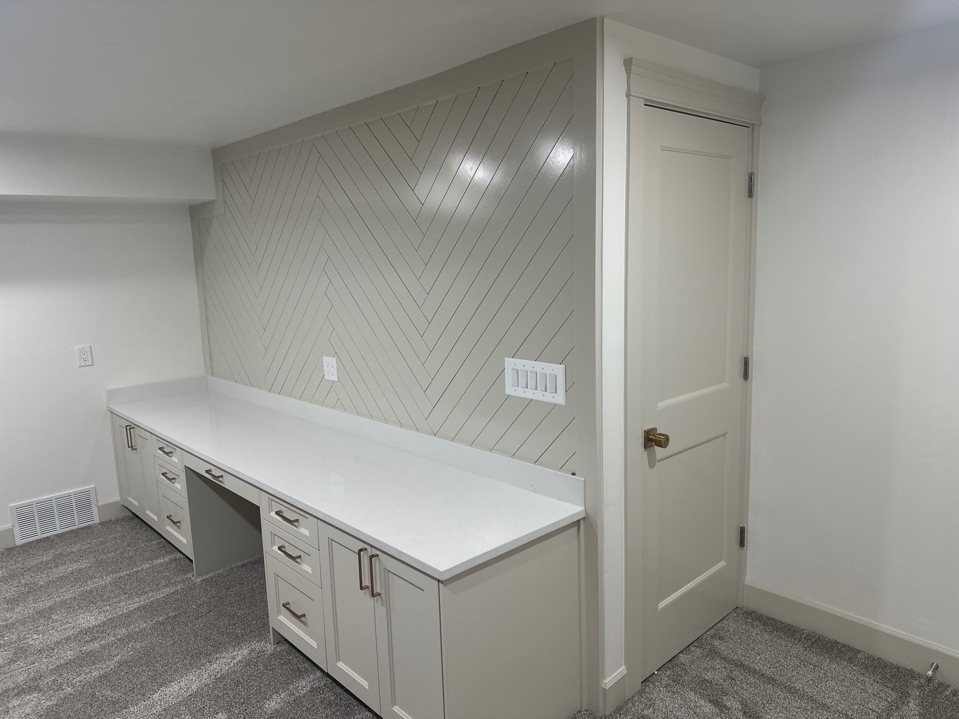 Built-in basement desk in Cottonwood Heights, Utah with a quartz top and a painted herringbone accent wall
