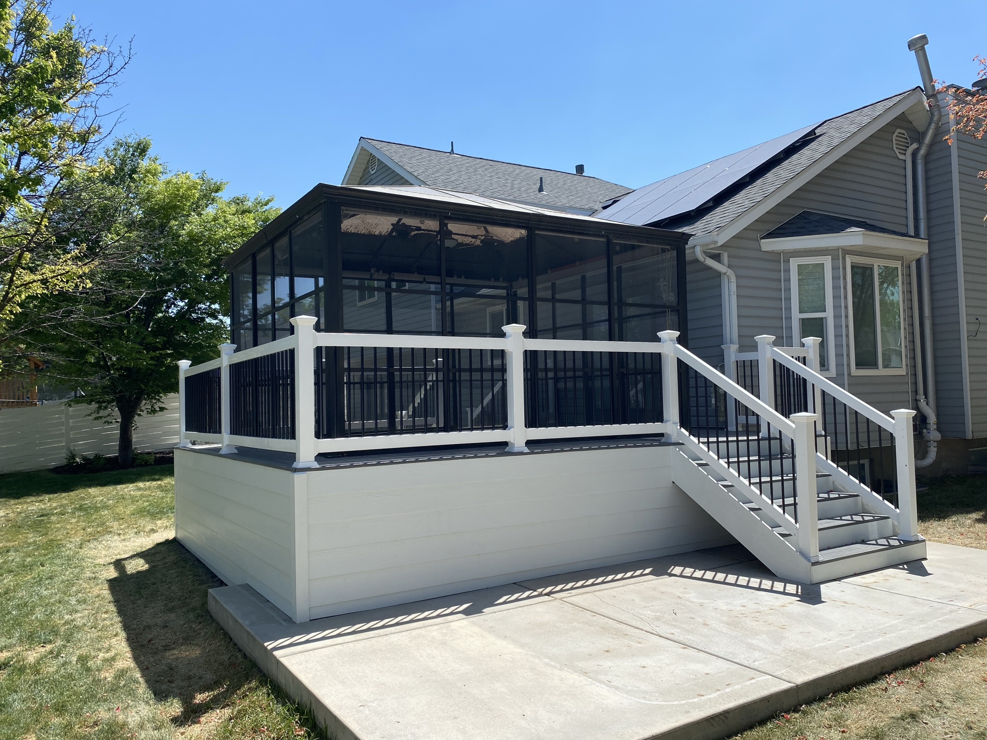 Screened deck enclosure with white composite decking and black balusters, a deck build in Holladay, Utah