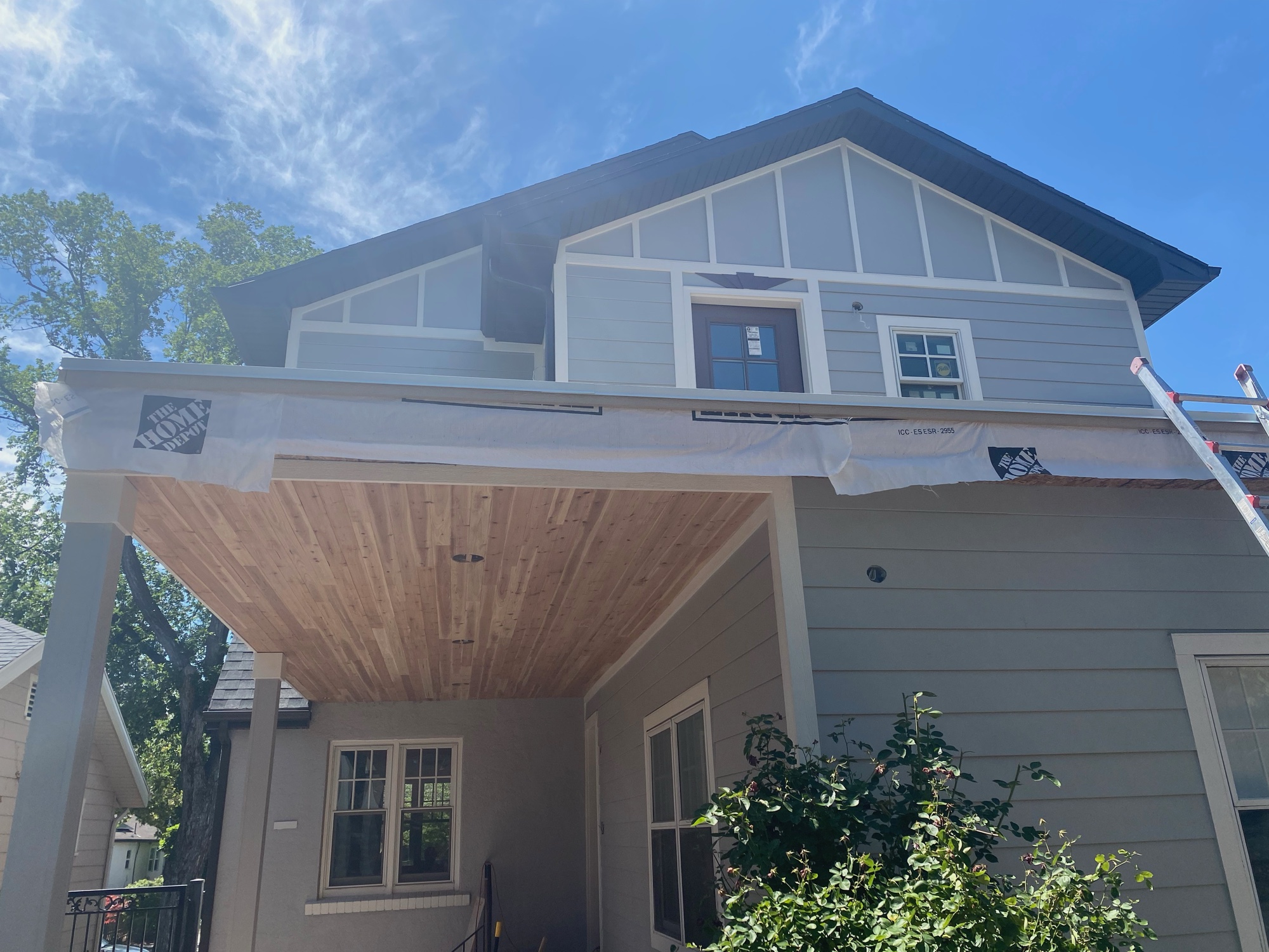 Second-story addition under construction in Sugarhouse, Salt Lake City, with new gray lap siding, a board-and-batten gable and a fresh cedar tongue-and-groove porch ceiling