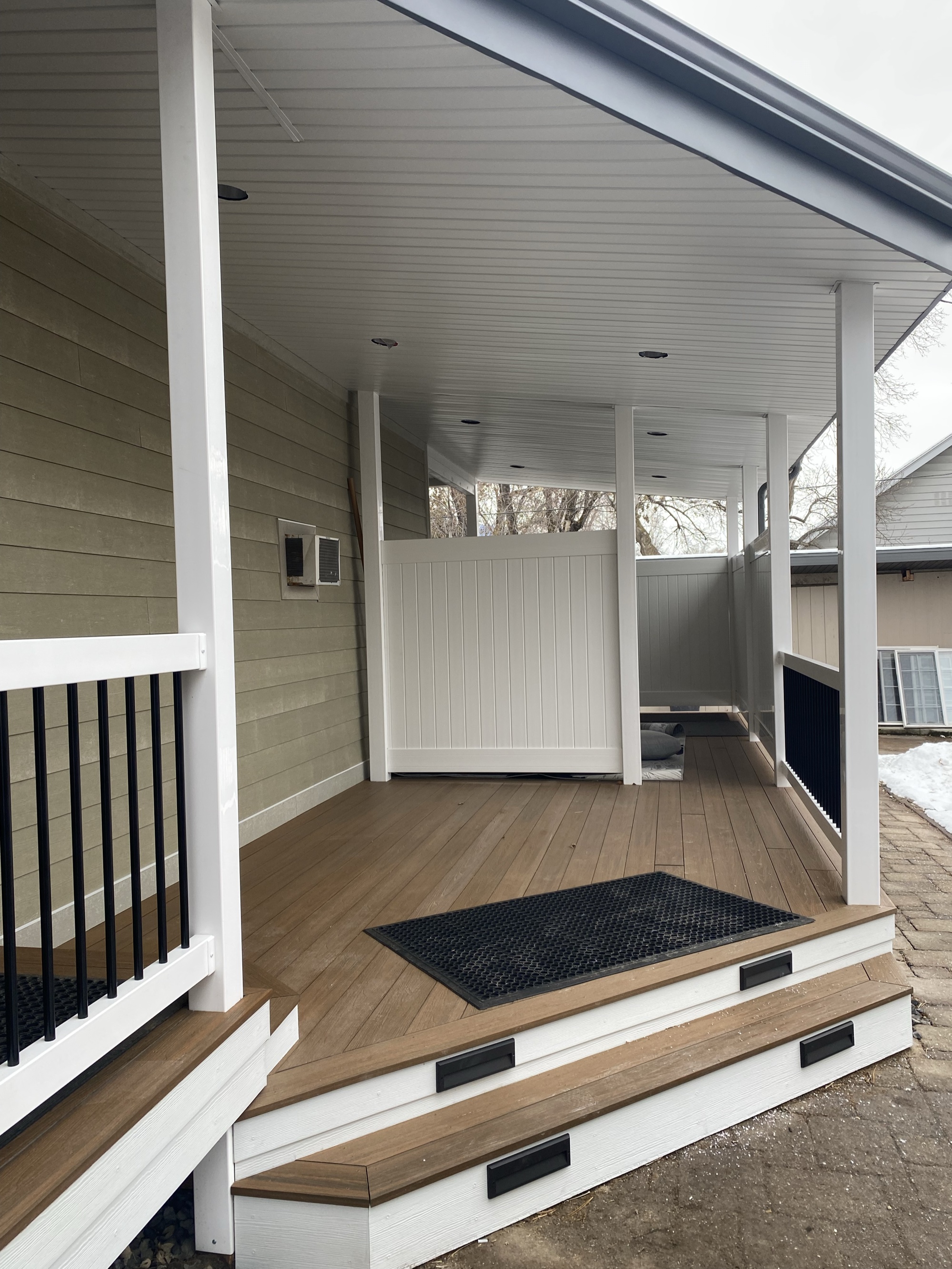 Covered porch addition in Cottonwood Heights, Utah with white vinyl privacy panels and tan composite decking