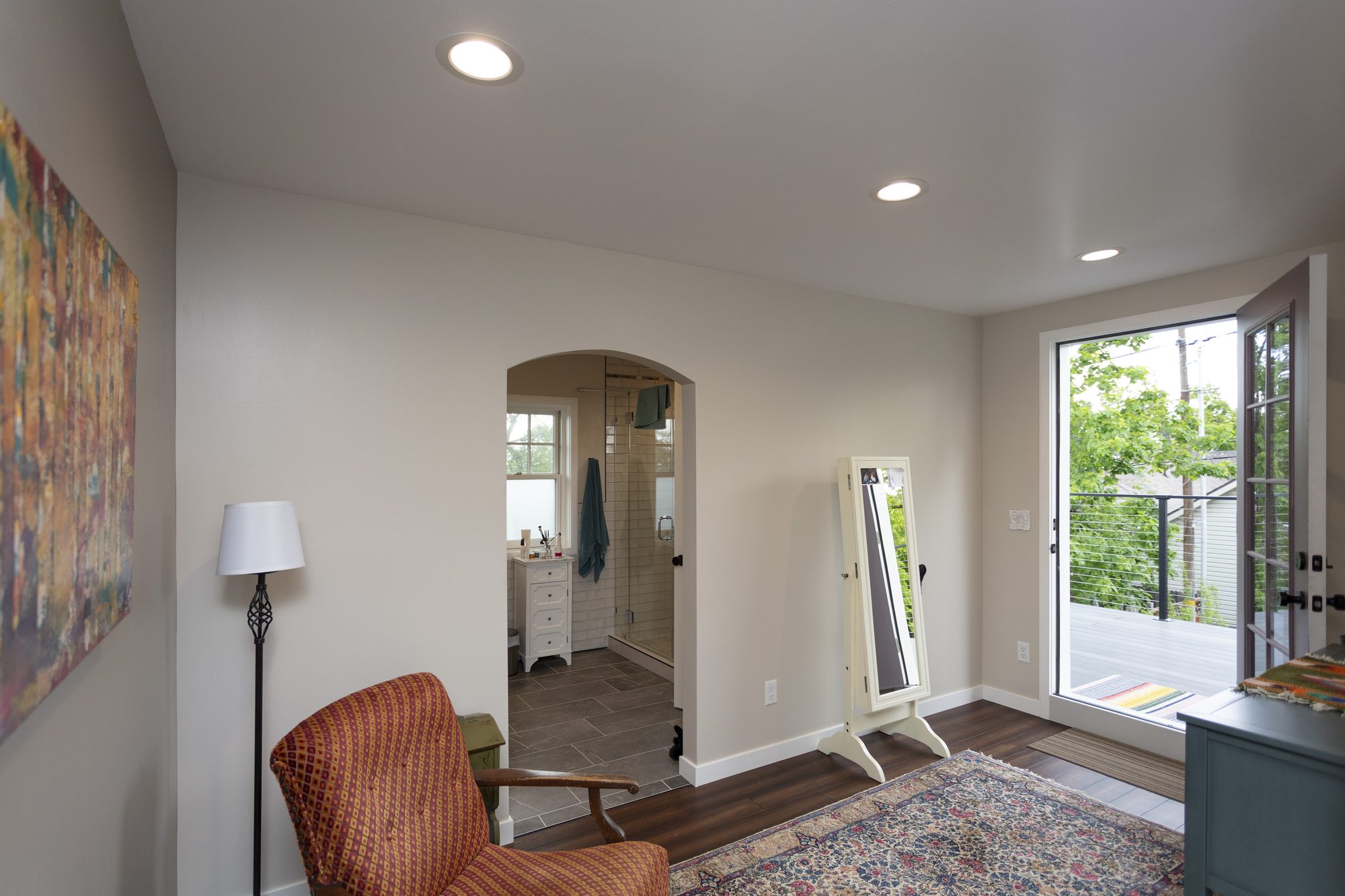 Primary suite in a second-story addition in Sugarhouse, Salt Lake City, looking through an arched opening into the ensuite bath with a door to a private deck